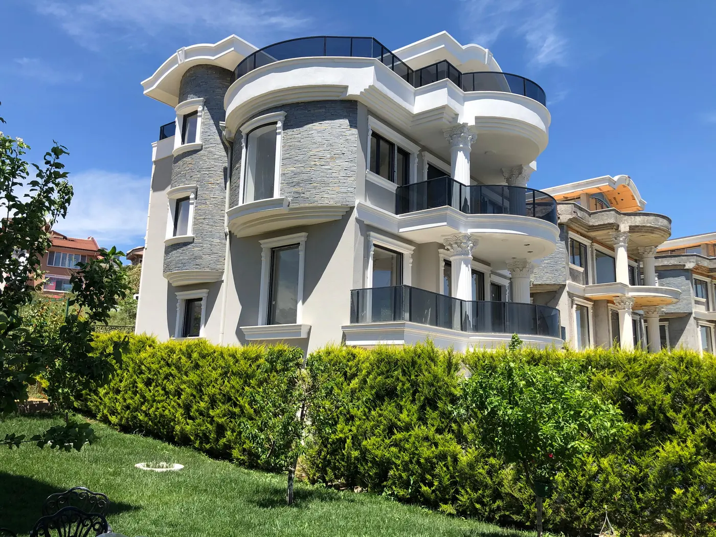 Bursa Nilüfer villa projesi — taş kaplama cephe, kolonlu balkonlar ve peyzaj